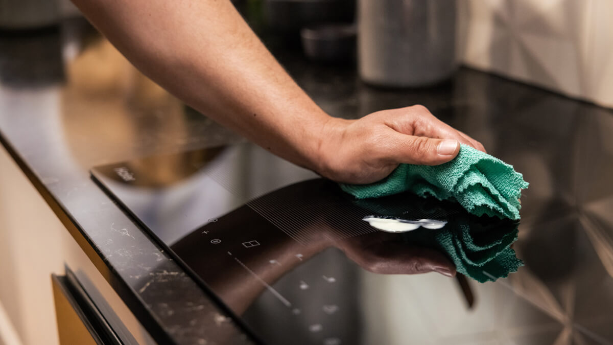 an induction cooktop being cleaned with a washcloth