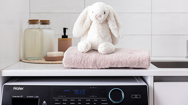 A stuffed bunny toy sits on a towel atop a Haier dryer
