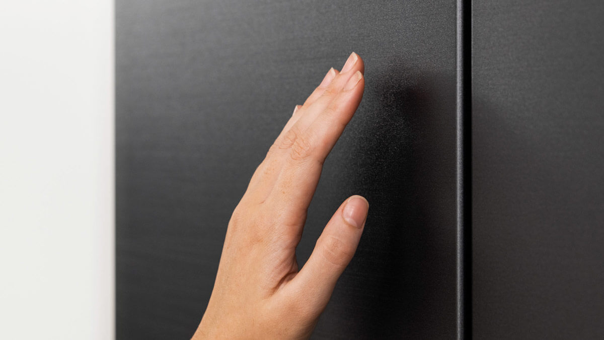 Hand touching the outside panel of fridge