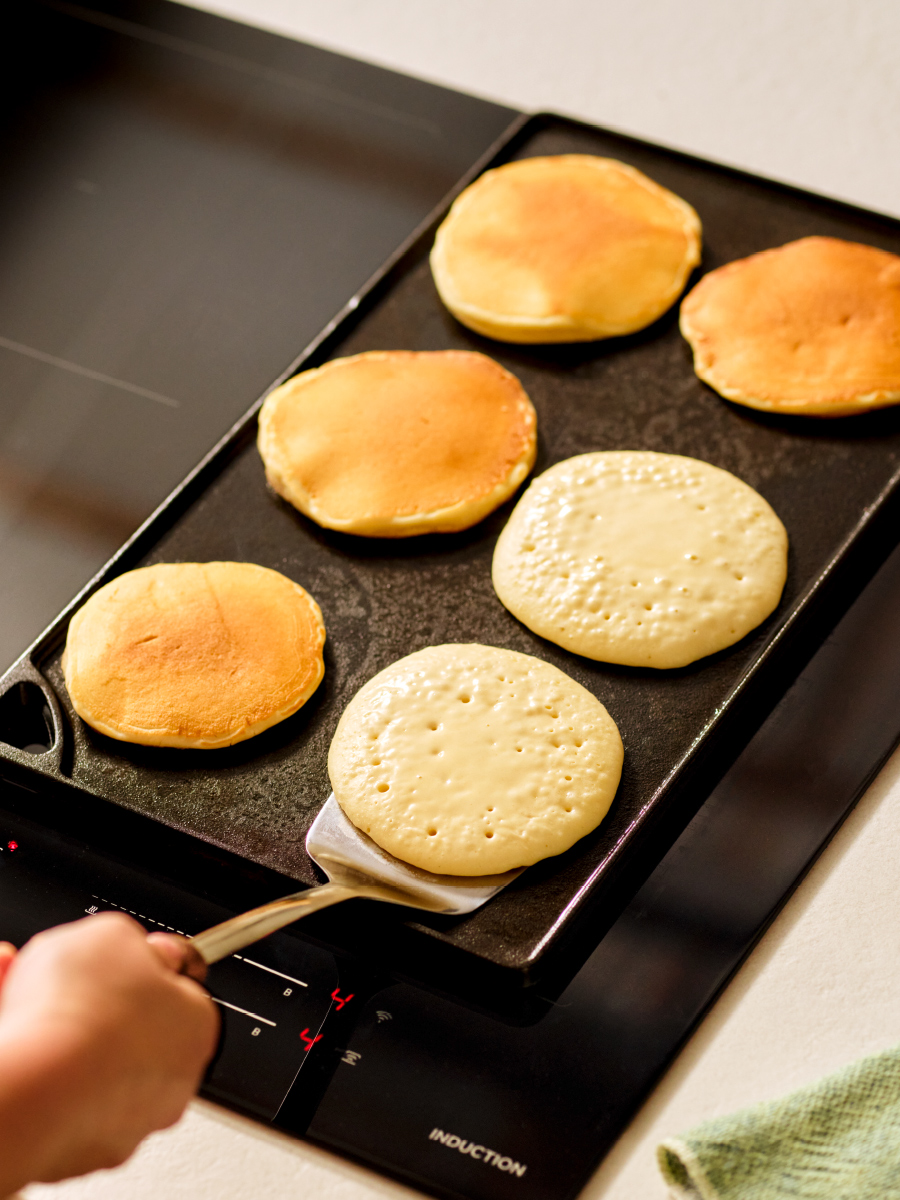 Cooking pancakes on a griddle plate on a cooktop