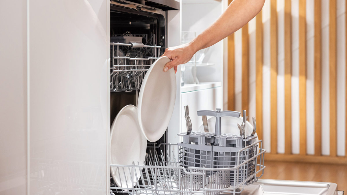 a dinner plate being placed into a drop door dishwasher